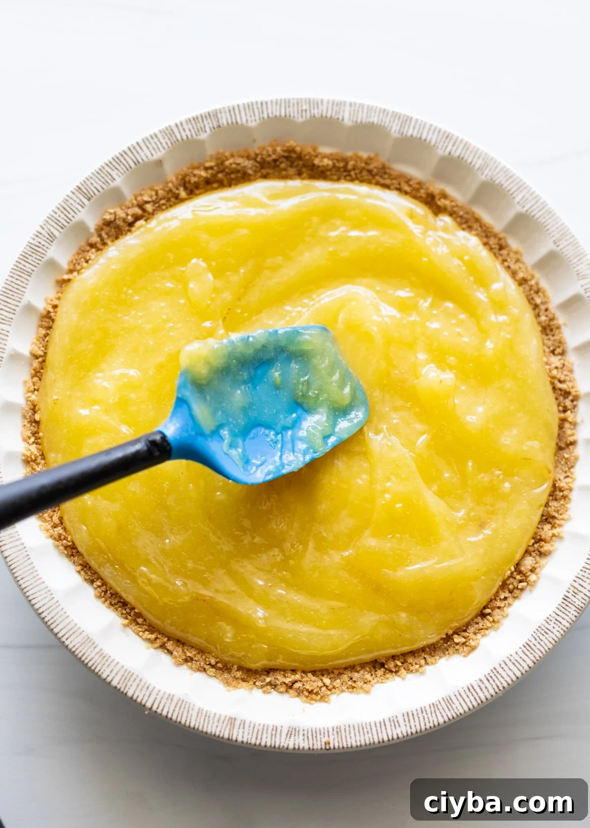 Person spreading lemon meringue over a graham cracker crust.