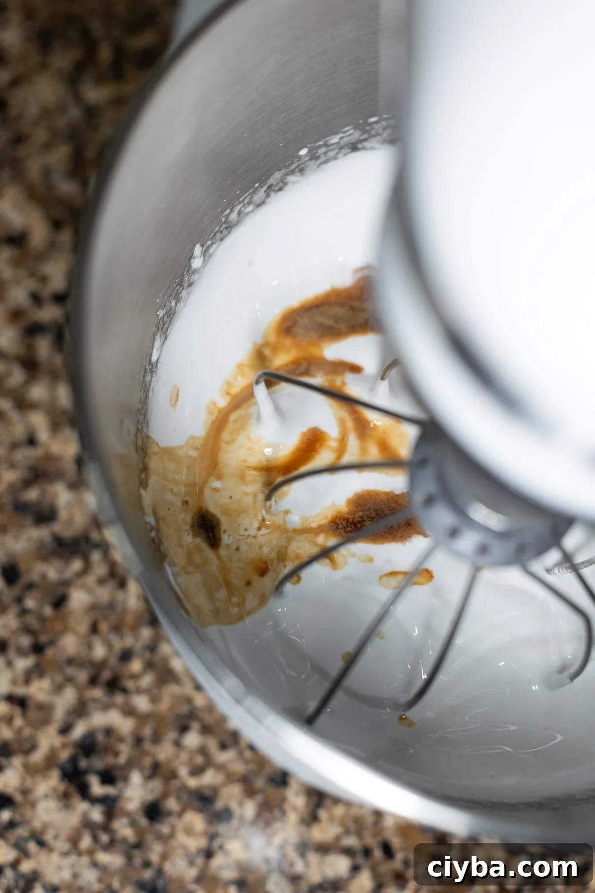 Person adding vanilla extract to homemade meringue.