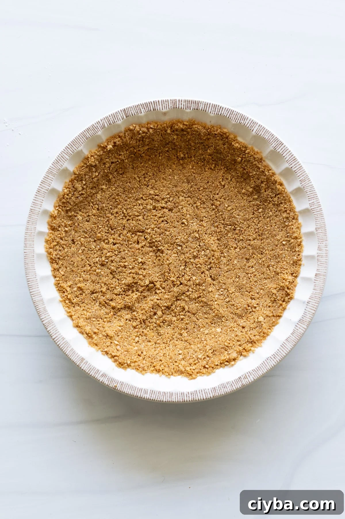 Person making a graham cracker crust and putting it in a pie dish.