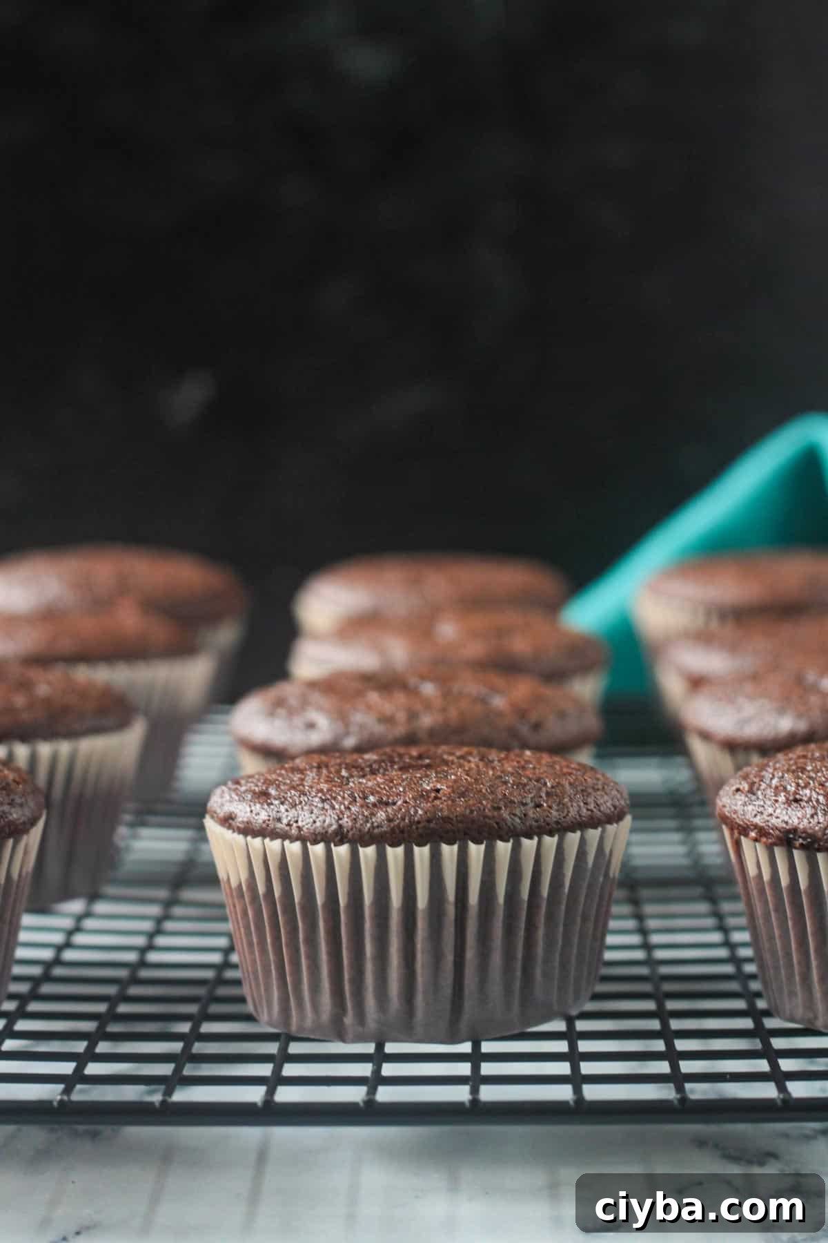Close up of one finished chocolate cupcake in a cupcake liner on a cooling rack.