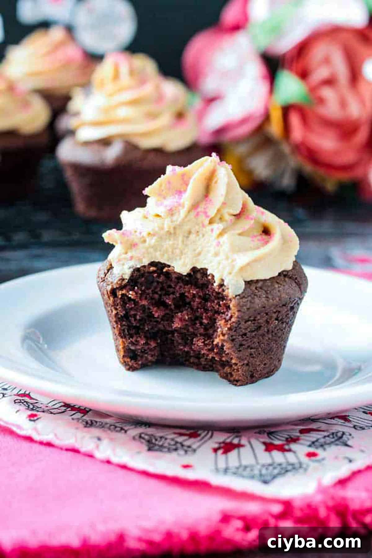 Chocolate cupcake with a bite taken out on a white plate.
