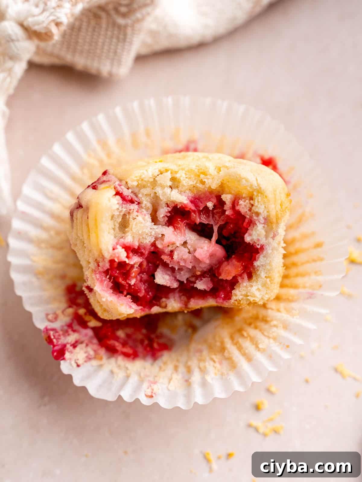 Lemon Raspberry Muffins with Zesty Lemon Glaze 10 A lemon muffin with raspberries that has a bite taken out of it.