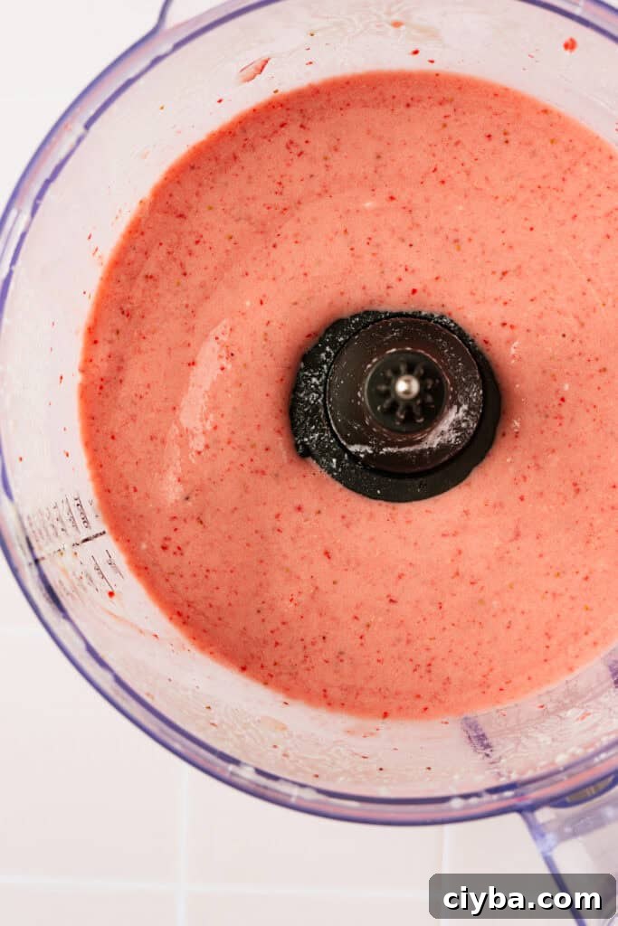 A blender with a blended strawberry milkshake in it.