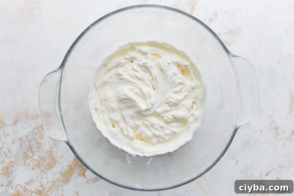 Freshly whipped cream in a glass mixing bowl with stiff peaks formed.