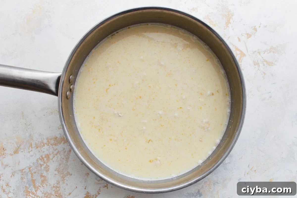 Custard ingredients in a saucepan before cooking, with visible egg yolks and milk.