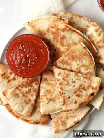 Plate of pizza quesadillas with marinara and pepperoni.