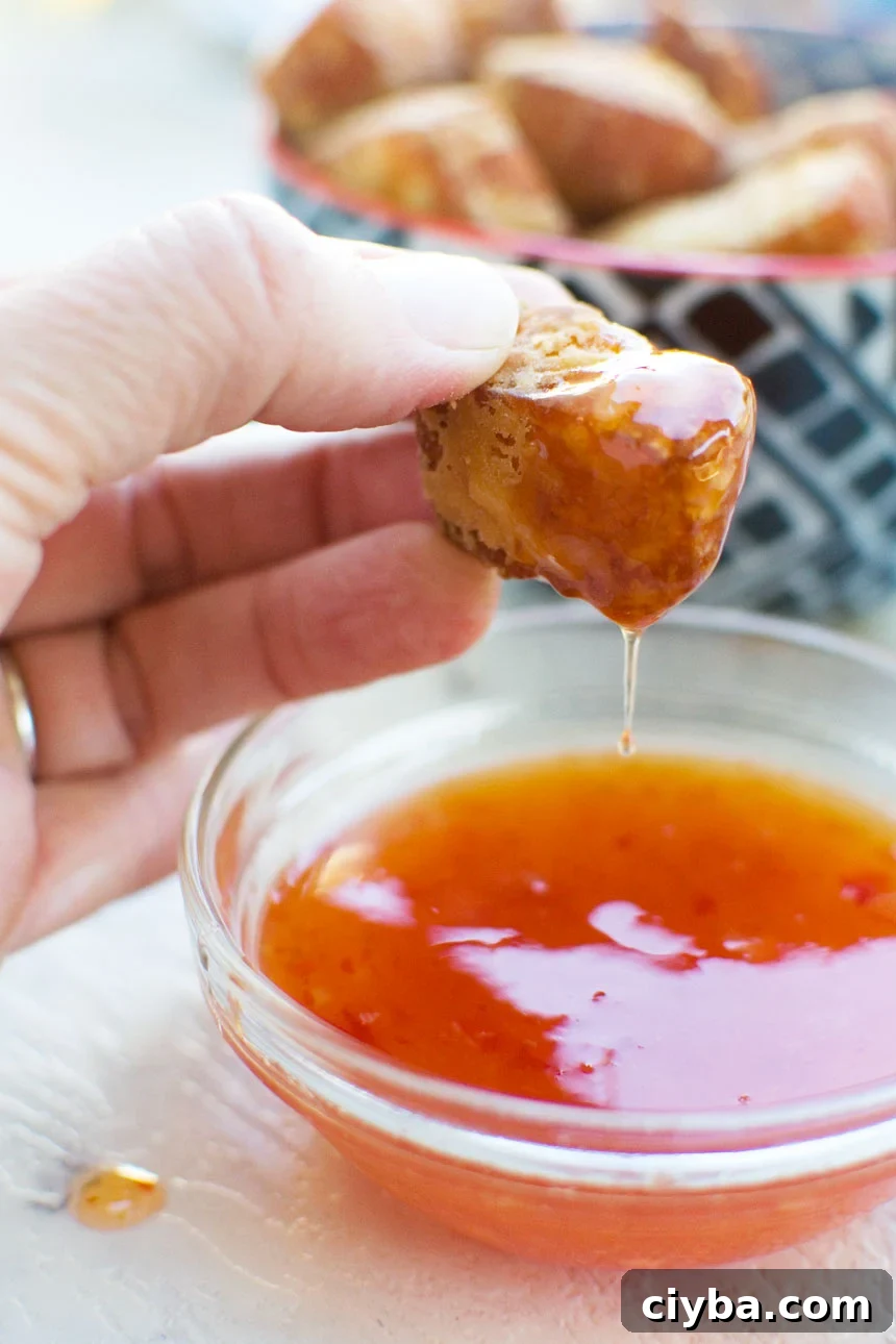 someone dipping a fried halloumi bite in a small dish of sweet chili sauce