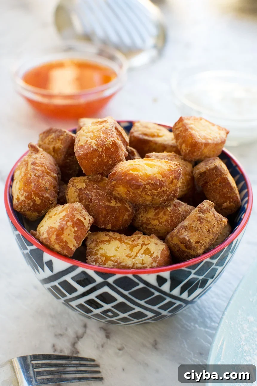 fried halloumi bites in a blue bowl up close with sweet chili sauce and greek yogurt in the background