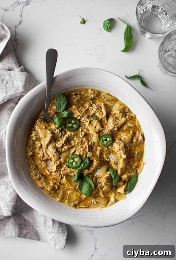 basil curry in a white bowl with a marble countertop and fresh basil leaves around it