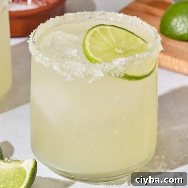 Classic Margarita Recipe: How to Make an Authentic Margarita 7 Cocktail glass with a classic margarita and lime wedge.