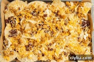 Chicken Nachos Recipe with Fresh Salsa and Avocado 10 This is a picture of a platter of chips with cheese, beans and cooked chicken on top before putting in the oven.