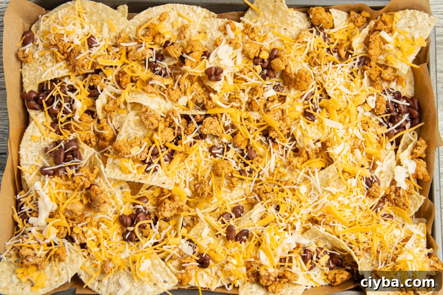 Chicken Nachos Recipe with Fresh Salsa and Avocado 6 This is a picture of a platter of chips with cheese, beans and cooked chicken on top before putting in the oven.