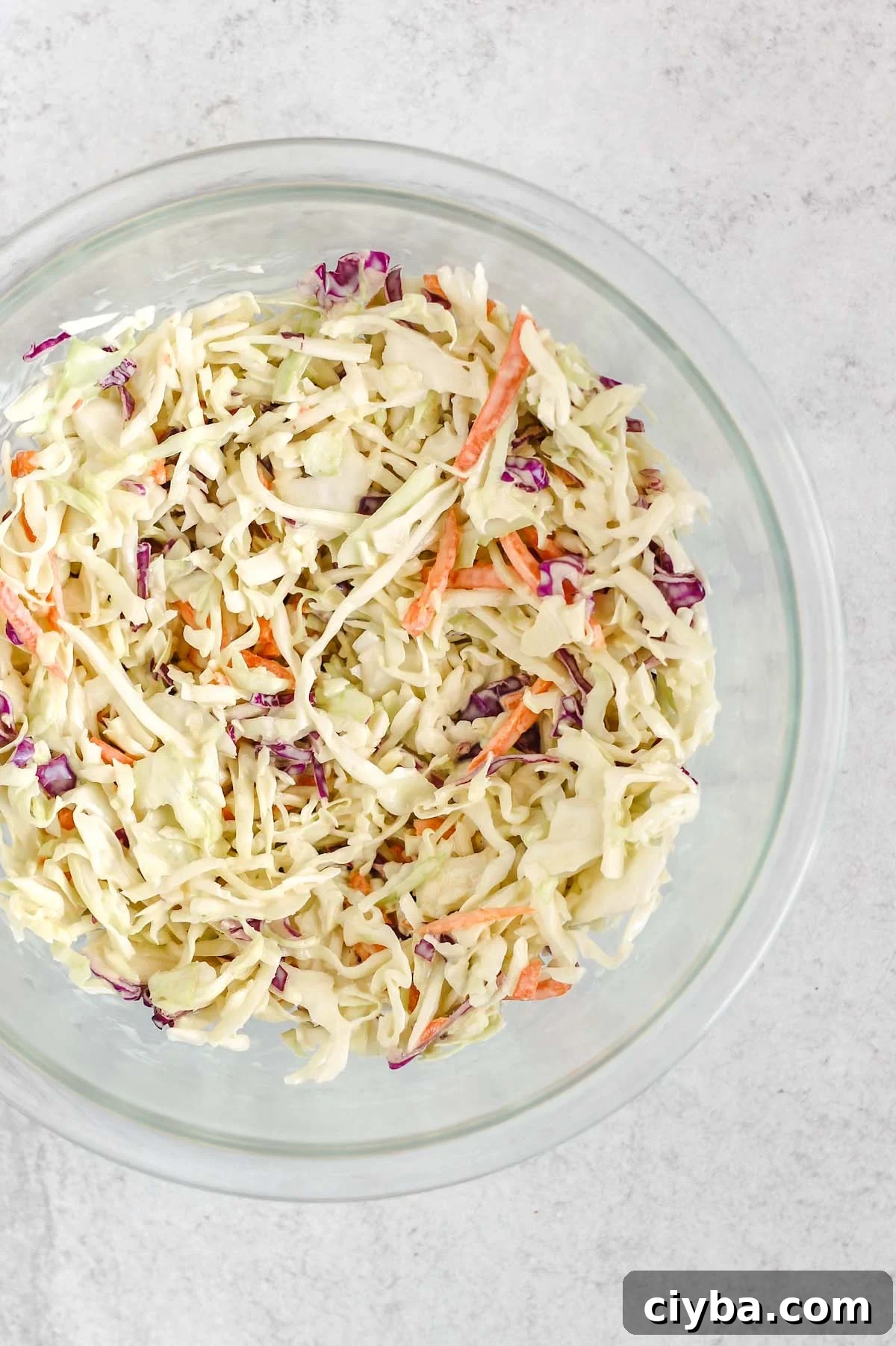 Creamy Whole30 and Paleo Coleslaw Recipe for BBQs and Meals 6 Coleslaw mixed with dressing in a mixing bowl.