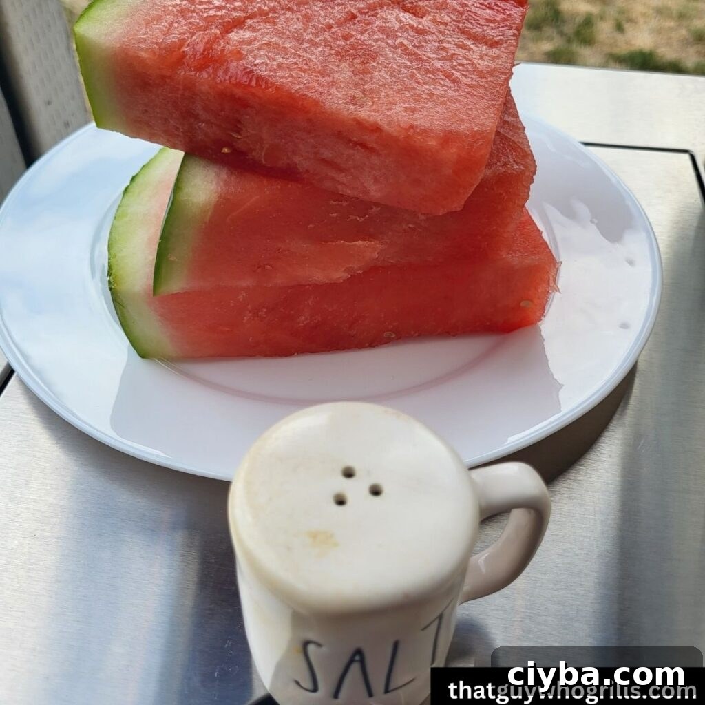 Raw watermelon on a white plate next to a salt shaker