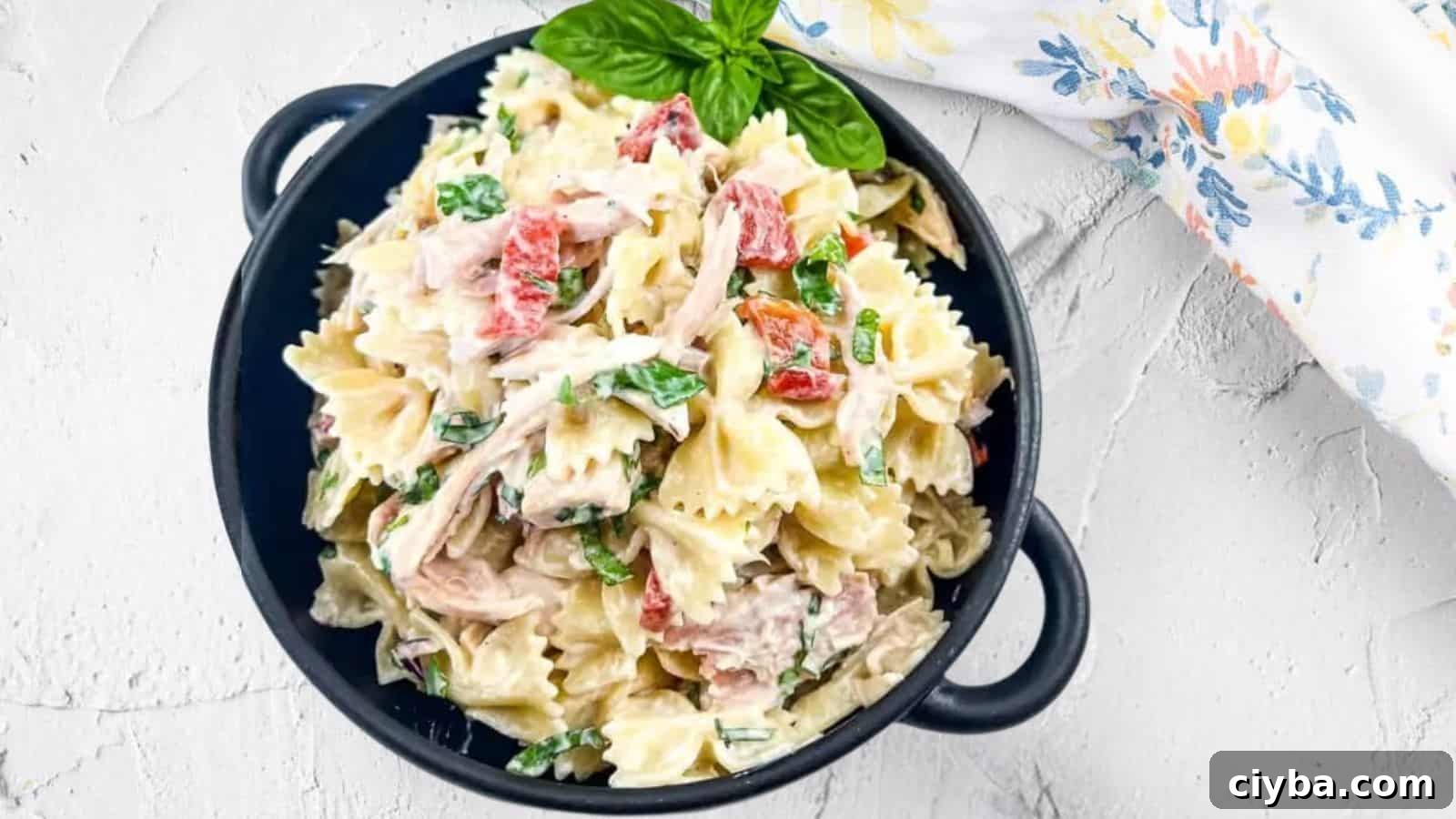 A black bowl filled with rotisserie chicken pasta salad.