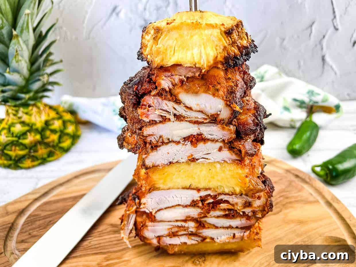 A stack of chicken and pineapple on a vertical skewer on a cutting board.