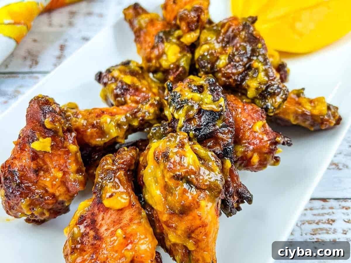 A plate of chicken wings on a white plate with a slice of mango.