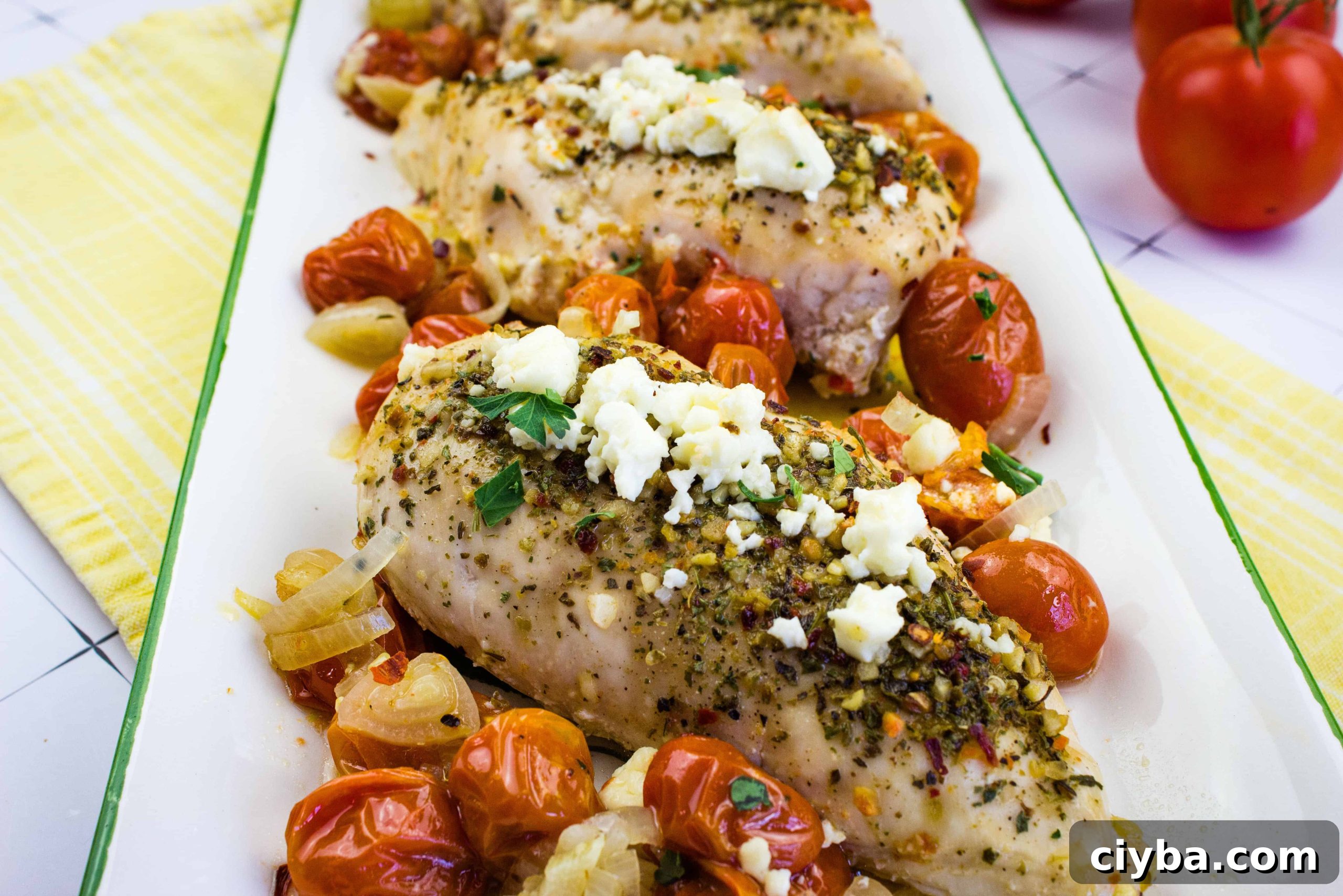 Mediterranean Chicken Bake with herbs, cheese and tomatoes in a platter.