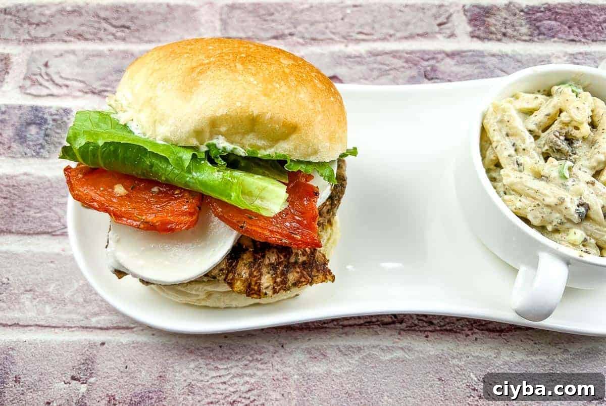 2 Grilled Chicken Caprese Sandwiches on a black plate.