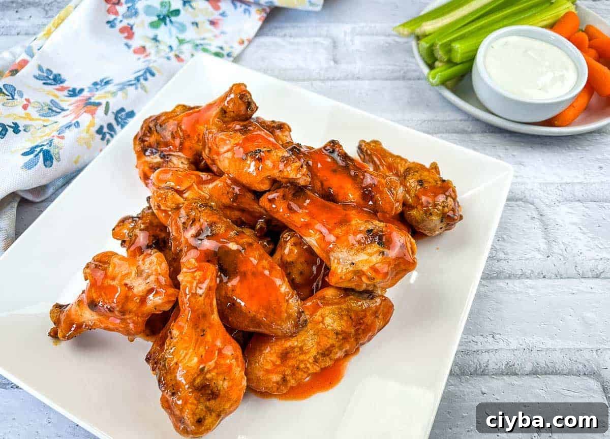 Chicken wings on a white plate with sauce and carrots.