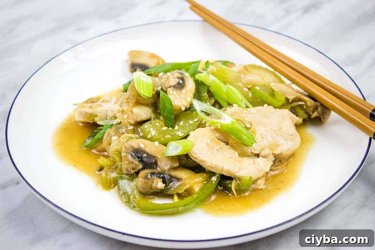A white plate with chicken and mushrooms in a sauce.