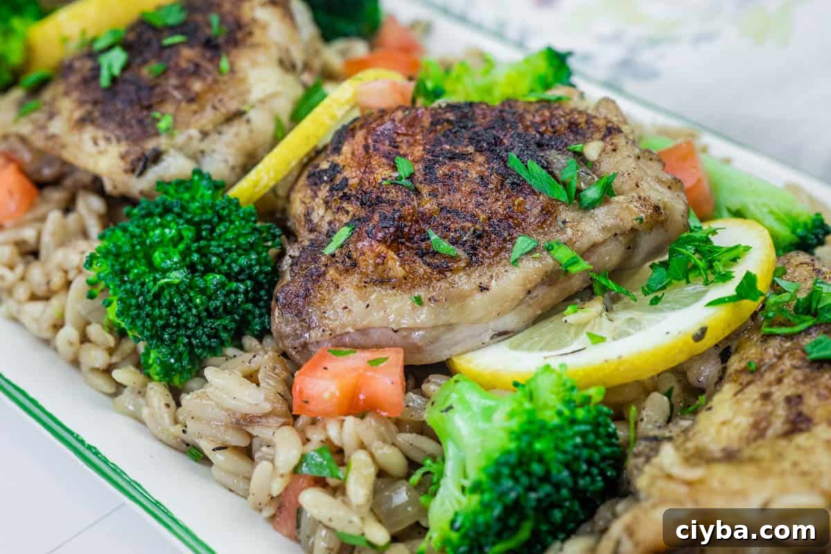 Lemon Chicken Broccoli Orzo Skillet, diced tomatoes, lemon slices, and parsley garnish.