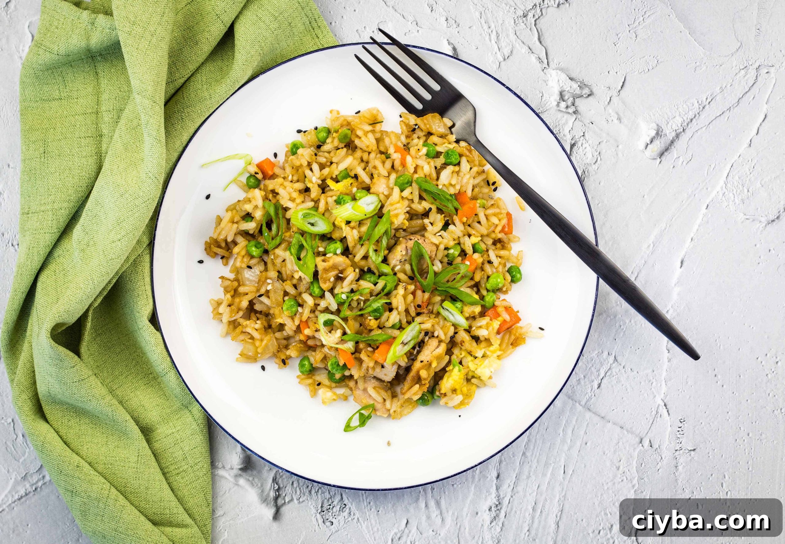 Chicken fried rice on a white plate with a green napkin.
