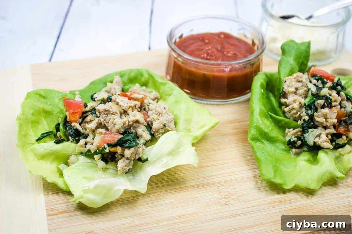 Two chicken parmesan lettuce wraps on a cutting board.