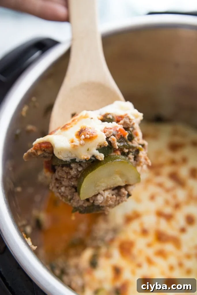 Wooden spoon with a bite of Instant Pot Zucchini Lasagna in the foreground and Instant Pot in the background