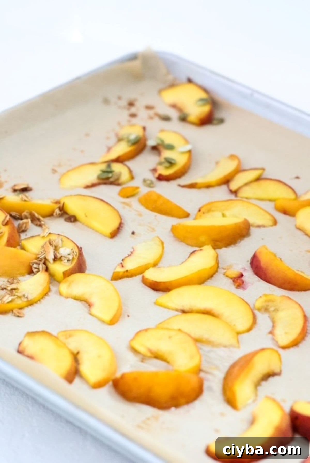 Sliced roasted peaches on a lined baking sheet.