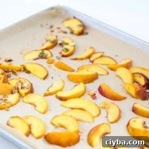 Roasted peach slices on a lined baking sheet.