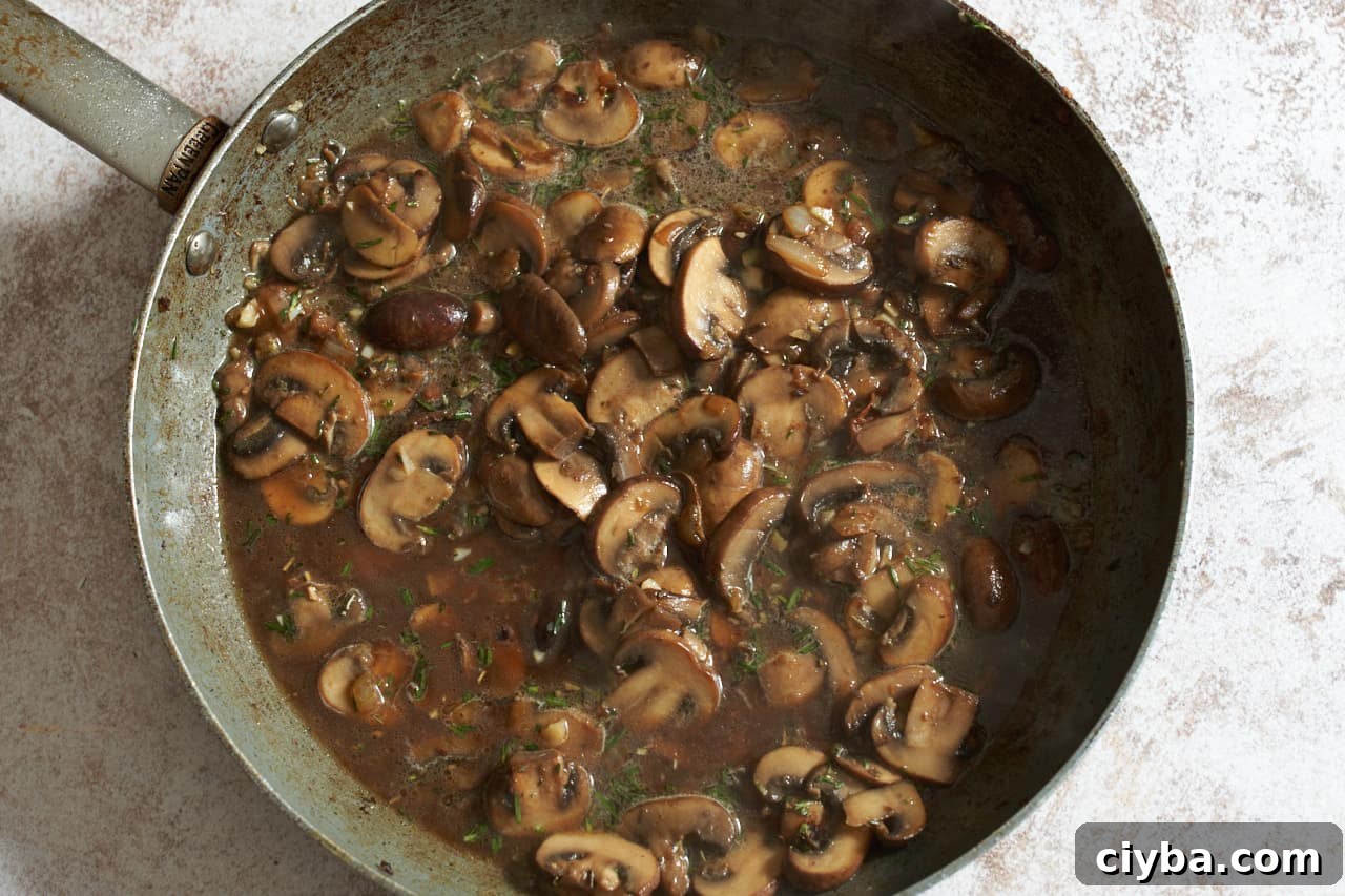 Mushrooms in broth in a skillet.