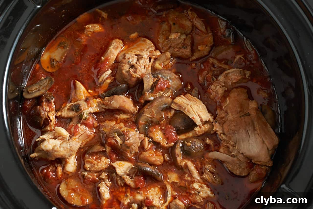 Finished chicken cacciatore in a black slow cooker.