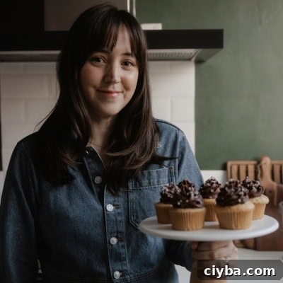 Ella from Alpine Ella is holding a cake stand with cupcakes on it.