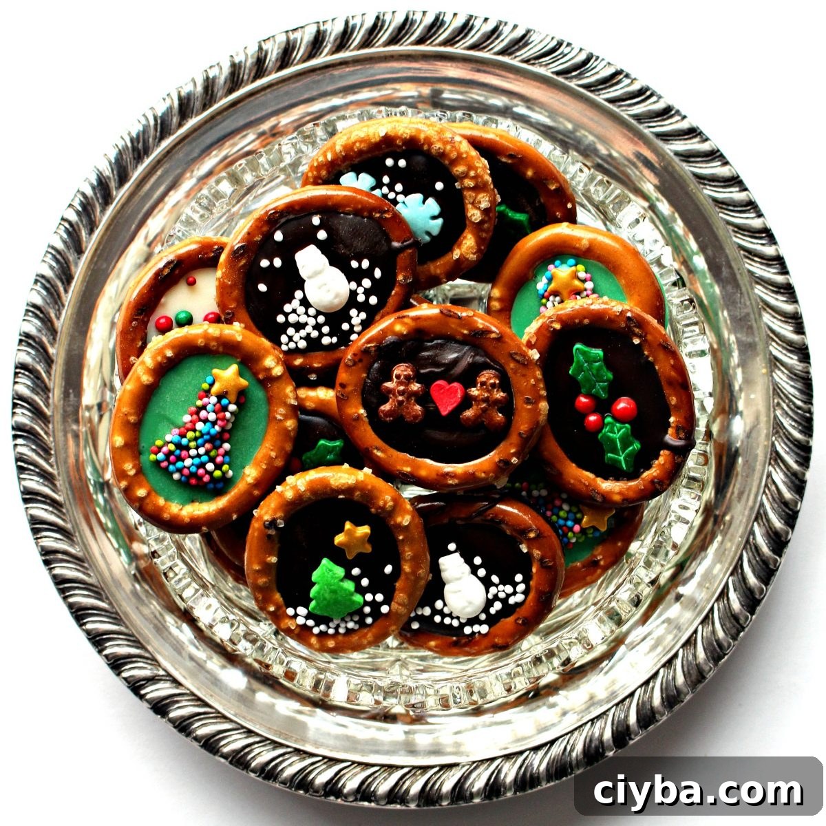 Pretzel rings with chocolate centers and sprinkle designs on a round silver platter.