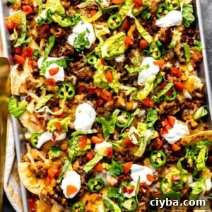 Sheet pan nachos with ground beef topped with sour cream and guacamole.