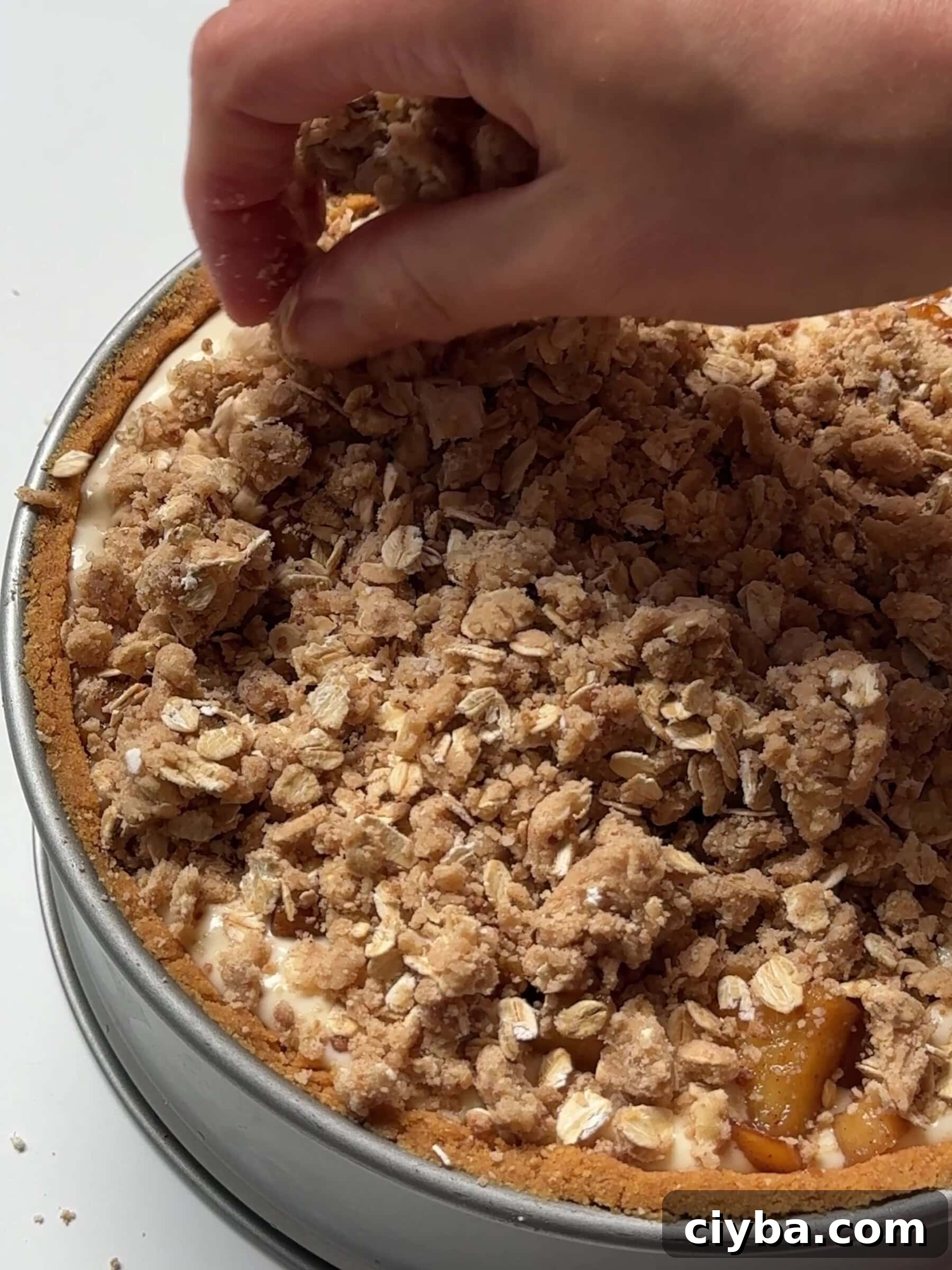 Sprinkling crumbles over apple and cheesecake mixture