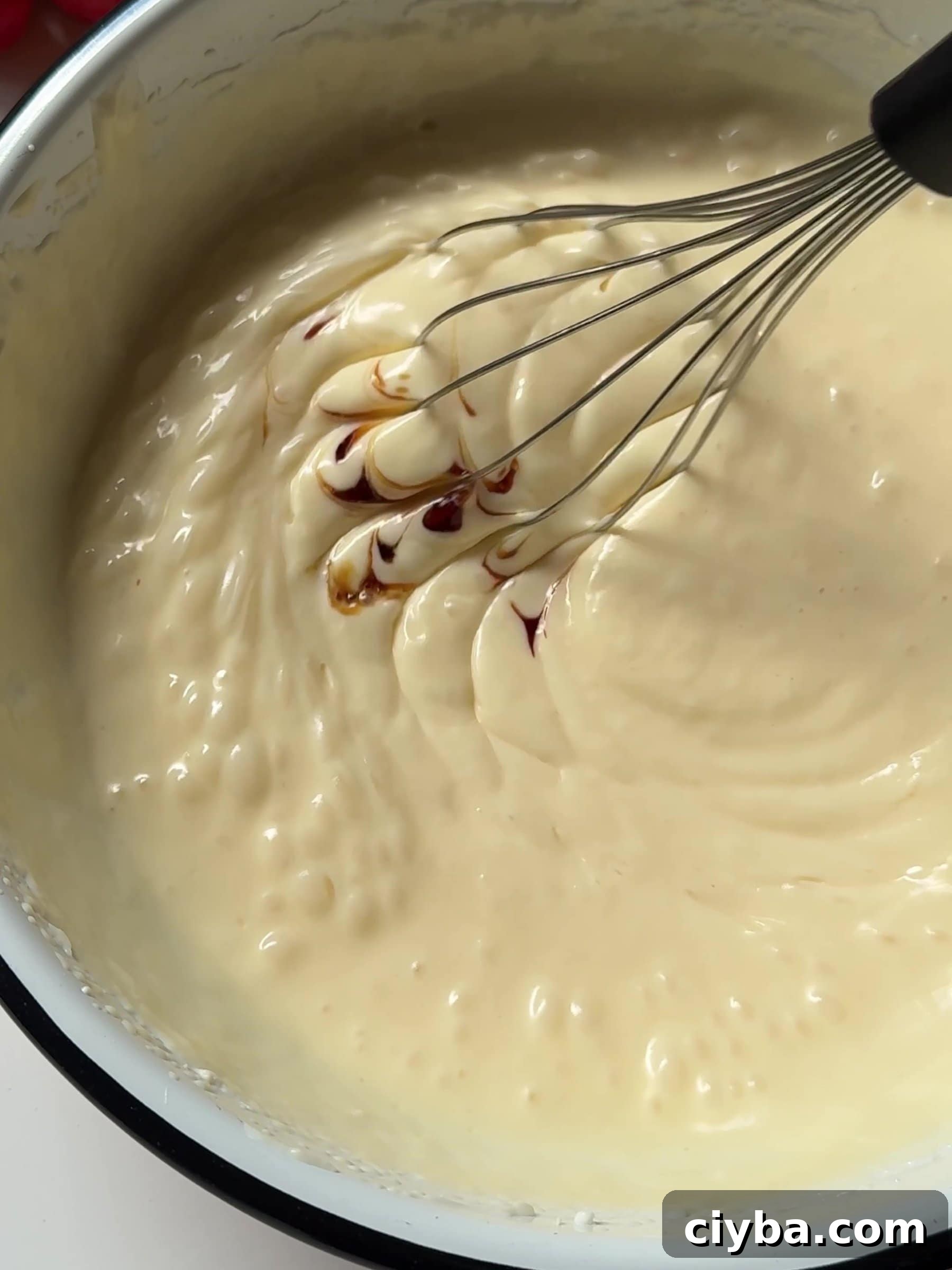 Whisking cheesecake filling and adding vanilla