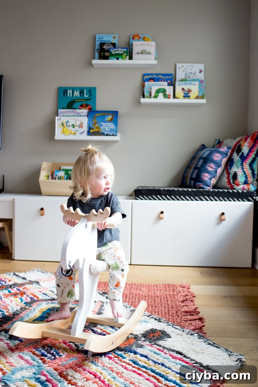 cute toddler girl on rocking moose in play room