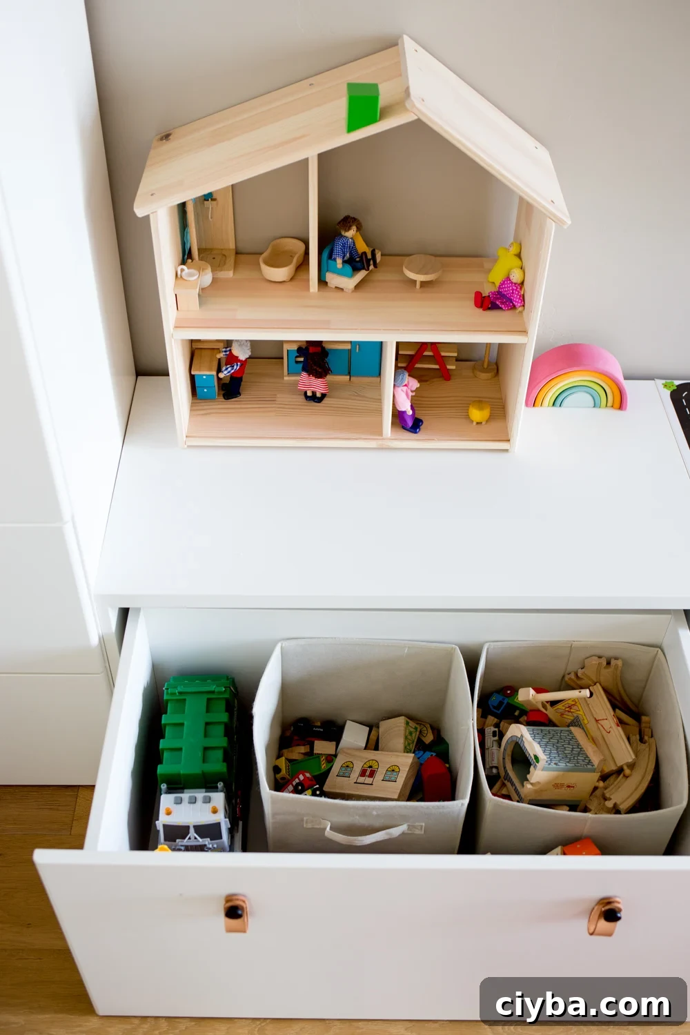white modern toy storage bench IKEA with toys in open drawer and simple wooden dollhouse on top