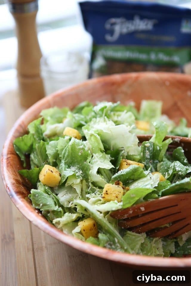 large wooden bowl of caesar salad topped with polenta croutons and parmesan walnut lemon vinaigrette