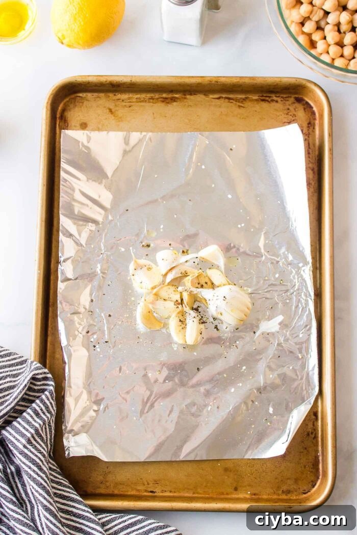 Whole cloves of garlic on a piece of foil on a roasting tray.