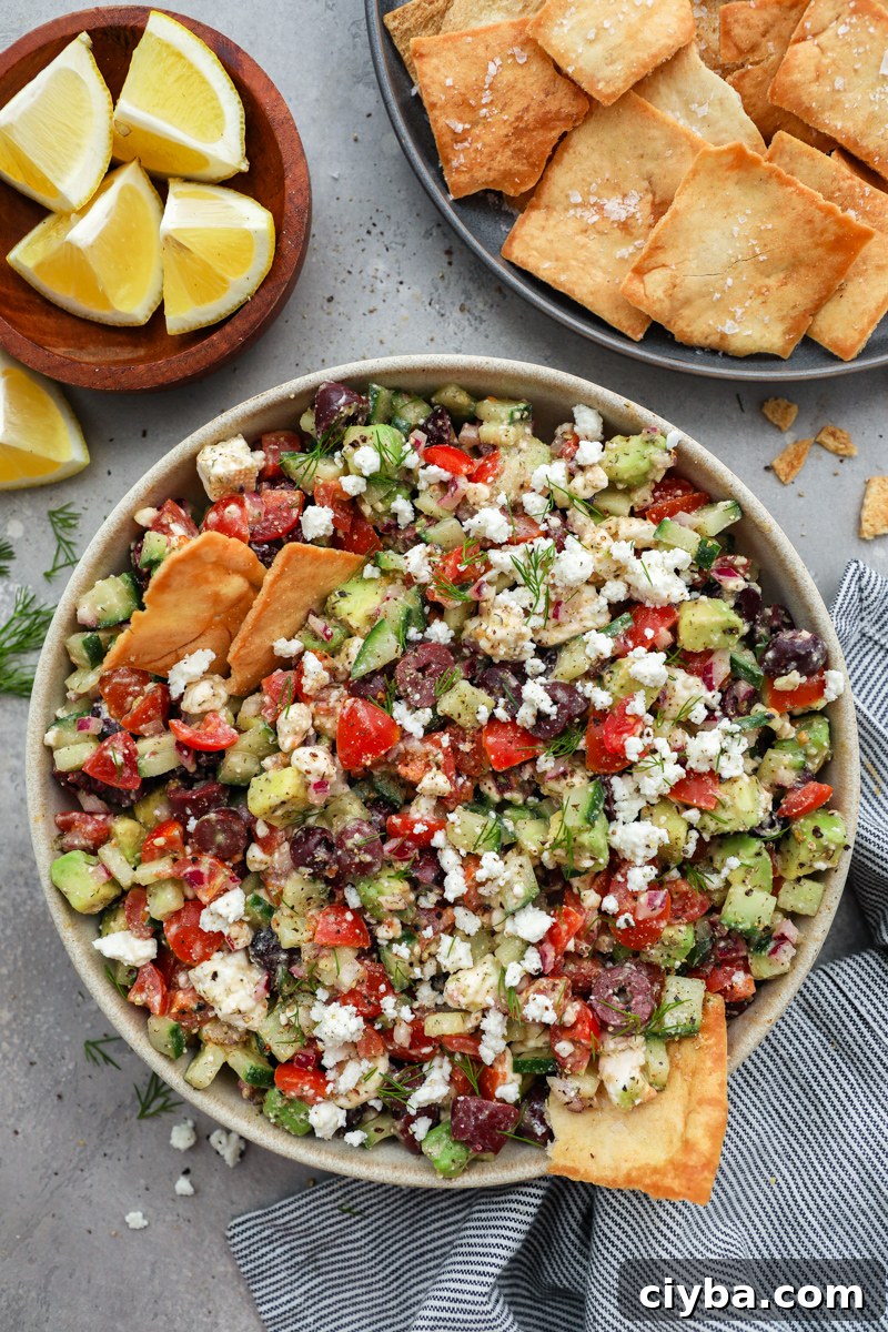 Mediterranean Avocado and Feta Salsa Recipe 6 A large serving bowl of Greek salsa being served with salty pita chips and fresh lemon wedges on the side