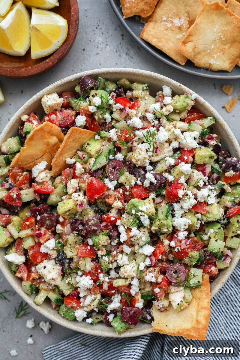 Mediterranean Avocado and Feta Salsa Recipe 8 A serving bowl filled with avocado and feta Mediterranean salsa with 2 crispy pita chips sticking out of it