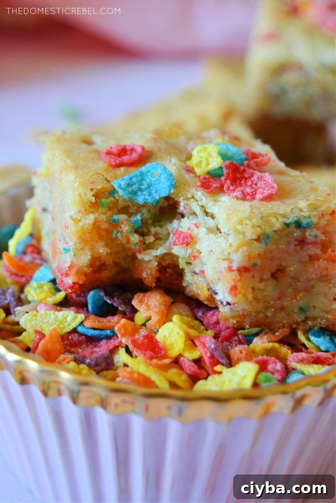 Closeup of a fruity pebble blondie with a bite missing in a bowl of cereal