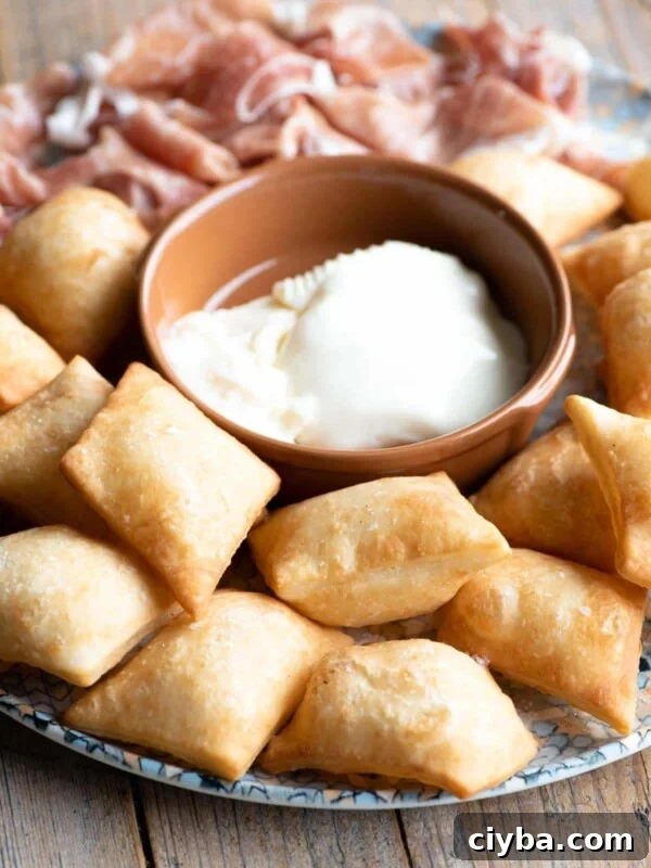 Gnocco Fritto (Italian fried dough) on a plate with cheese and prosciutto.