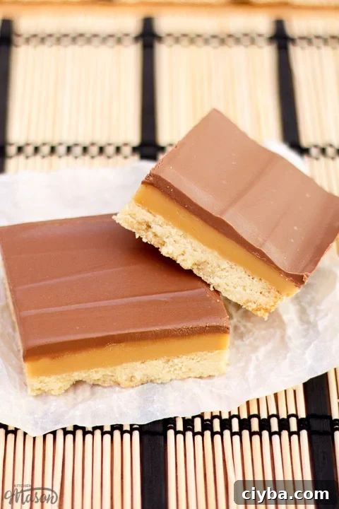 Millionaire's shortbread bar leaning on another bar on scrunched up white baking paper