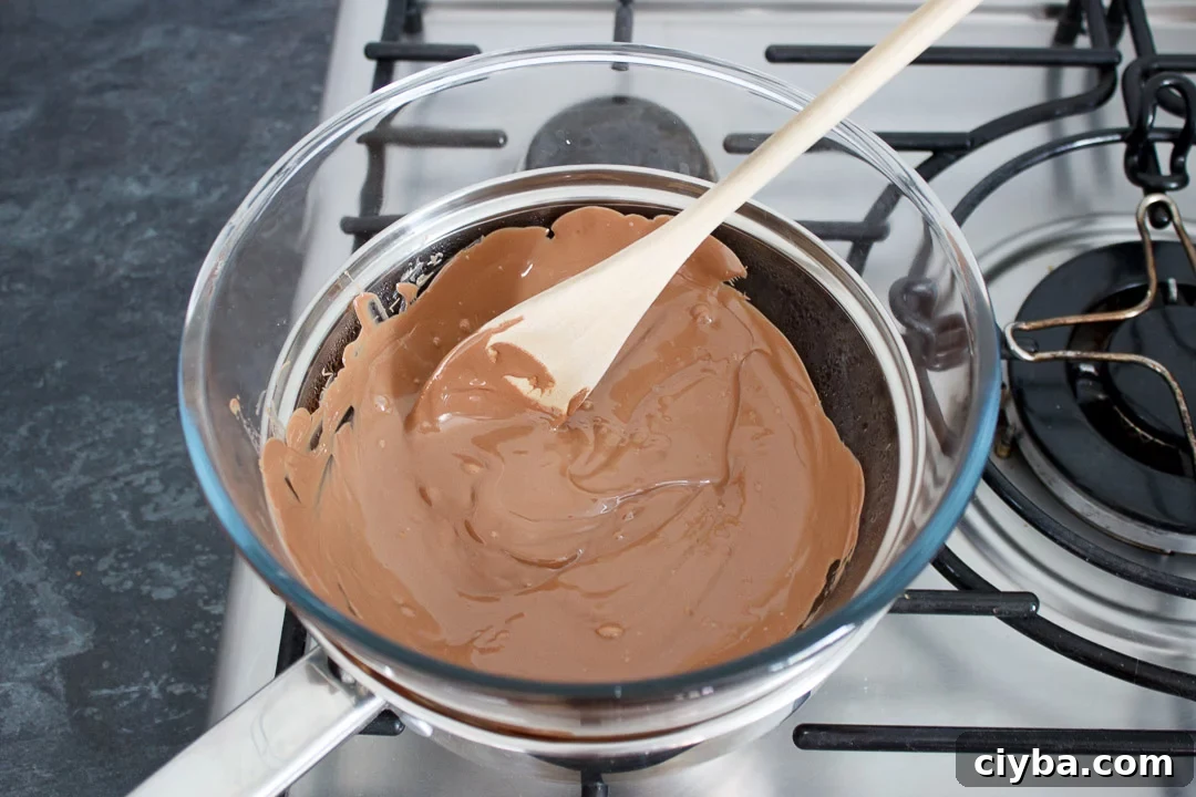 Milk chocolate being melted in a glass bowl set over a pan of barely simmering water on the hob.
