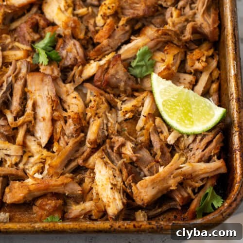 Crispy pork carnitas on a sheet pan garnished with lime and cilantro.