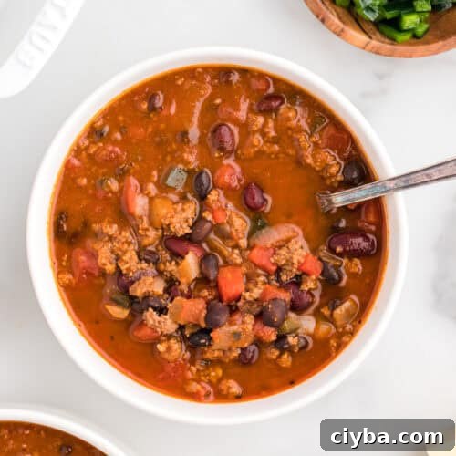 A bowl of chili sitting on a white table.